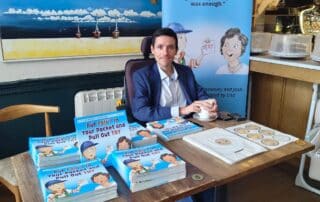 Put Can't In Your Pocket and Pull out Try book launch image. Josh Wintersgill sat at a table with a coffee and copies of the book.